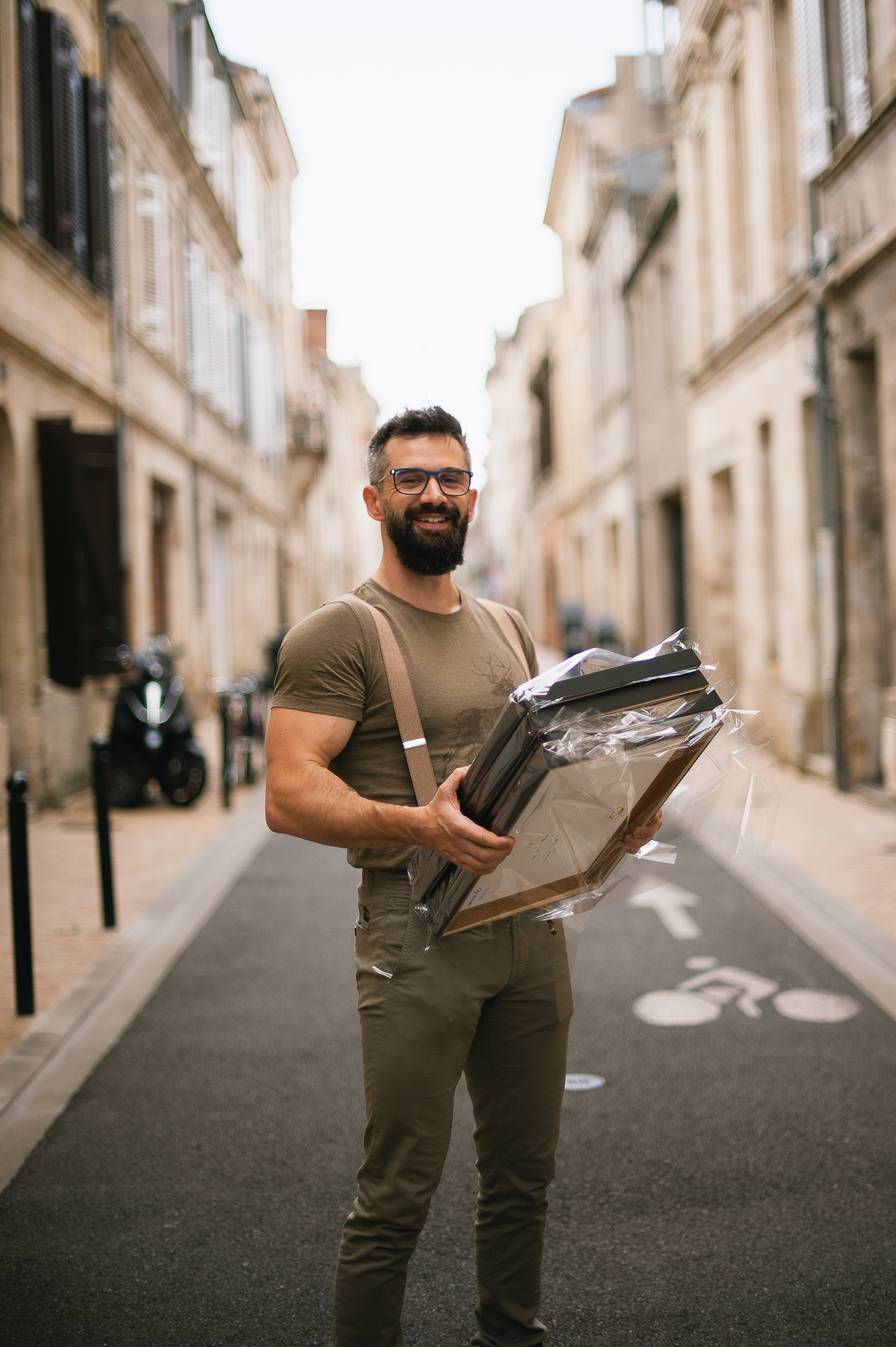 Un homme dans la rue qui sourit et tient des tirages photos dans ses mains